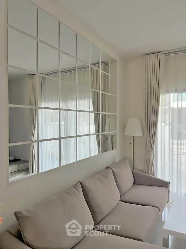 Elegant living room with modern sofa and large mirrored wall, enhancing natural light and spaciousness.