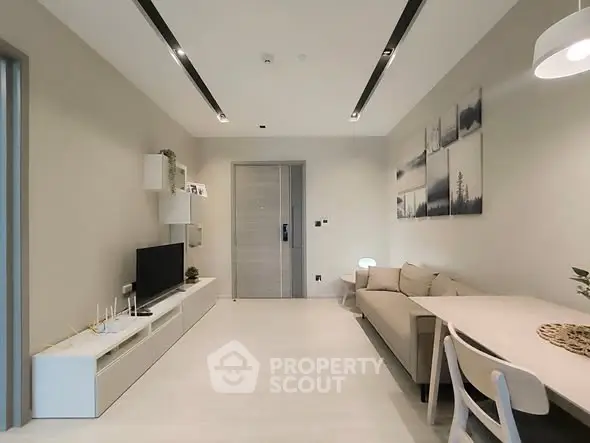 Modern living room with sleek furniture and minimalist decor, featuring a cozy sofa and wall-mounted TV.