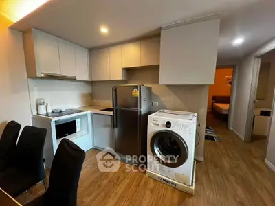 Modern kitchen with appliances including fridge and washing machine in cozy apartment.