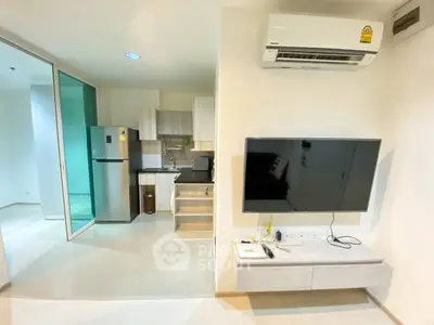 Modern apartment interior with sleek kitchen and wall-mounted TV, featuring air conditioning and stylish cabinetry.
