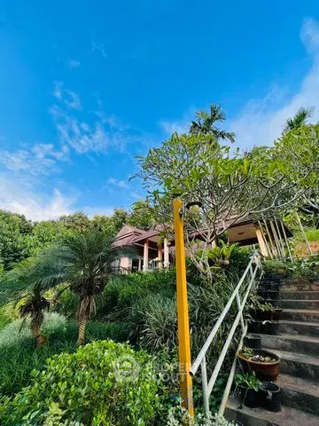 Stunning tropical garden view with lush greenery and charming villa under clear blue sky.