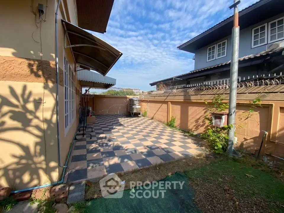 Charming backyard with checkered patio and sunny garden space, perfect for outdoor relaxation and entertainment.