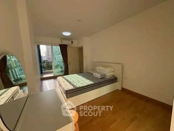 Spacious bedroom with balcony access and city view in modern apartment.
