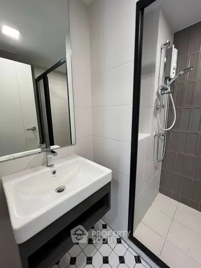 Modern bathroom with sleek sink and shower area in contemporary apartment.