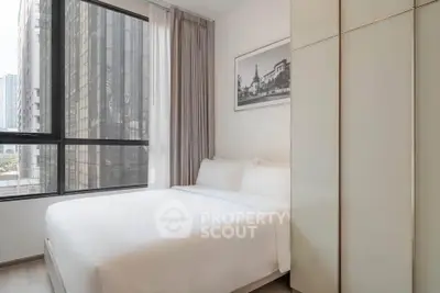 Modern bedroom with large window and city view in a high-rise apartment.