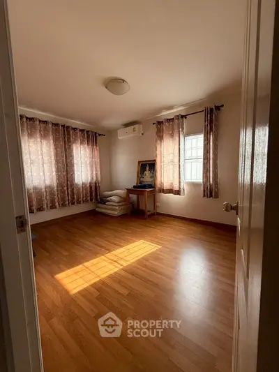 Spacious bedroom with wooden flooring and natural light