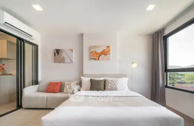 Modern bedroom with cozy sofa and large windows offering natural light.