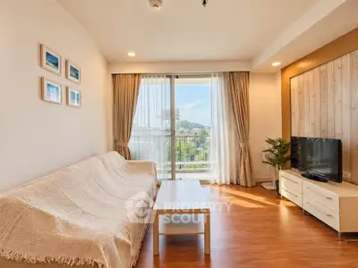 Bright living room with cozy sofa, TV, and large window offering scenic view.
