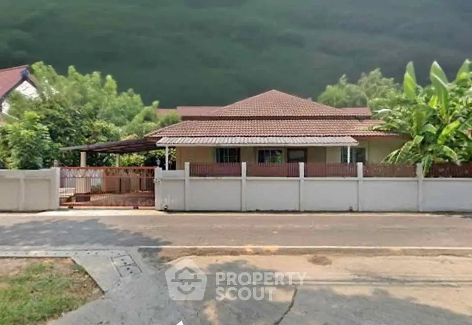 Charming single-story house with tiled roof and lush greenery in a serene neighborhood.