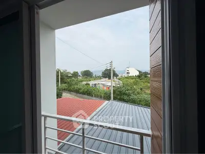 Scenic view from a balcony overlooking rooftops and greenery, perfect for relaxation.