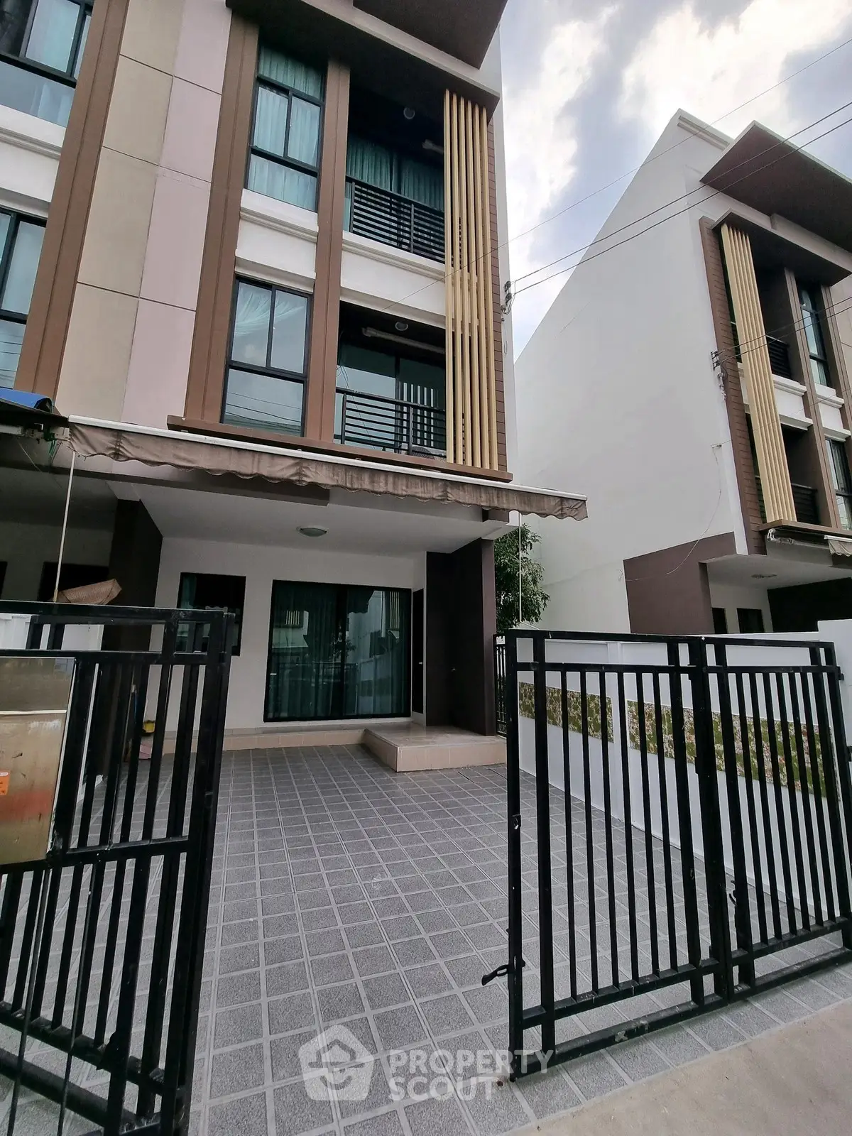 Modern townhouse exterior with gated entrance and tiled driveway