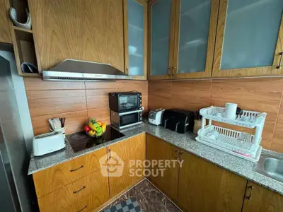 Modern kitchen with wooden cabinets and granite countertops, featuring appliances and a cozy layout.