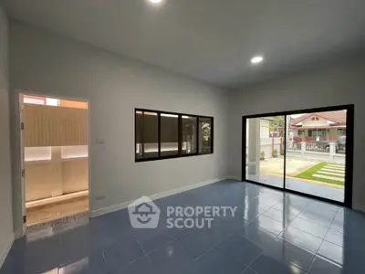 Spacious living room with blue tile flooring and large windows offering natural light.