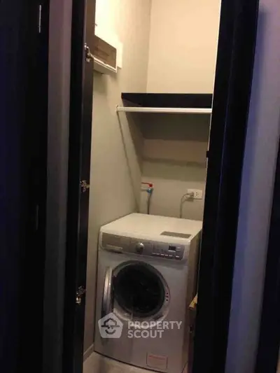 Compact laundry room with modern washing machine and shelving.
