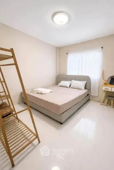 Cozy minimalist bedroom with natural light and modern furnishings.