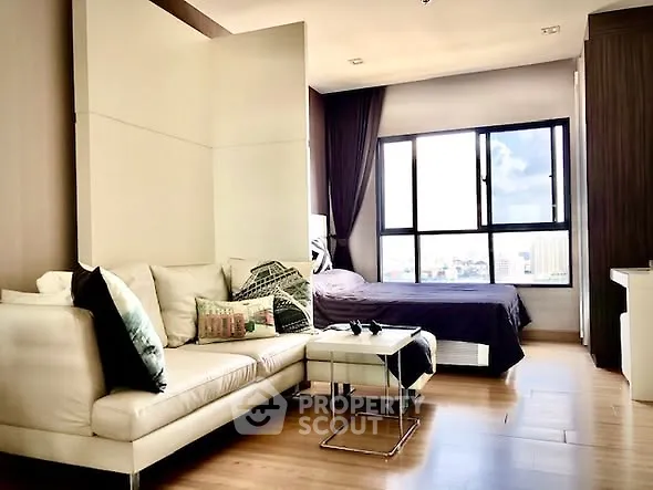 Modern studio apartment with cozy living area and large window view.