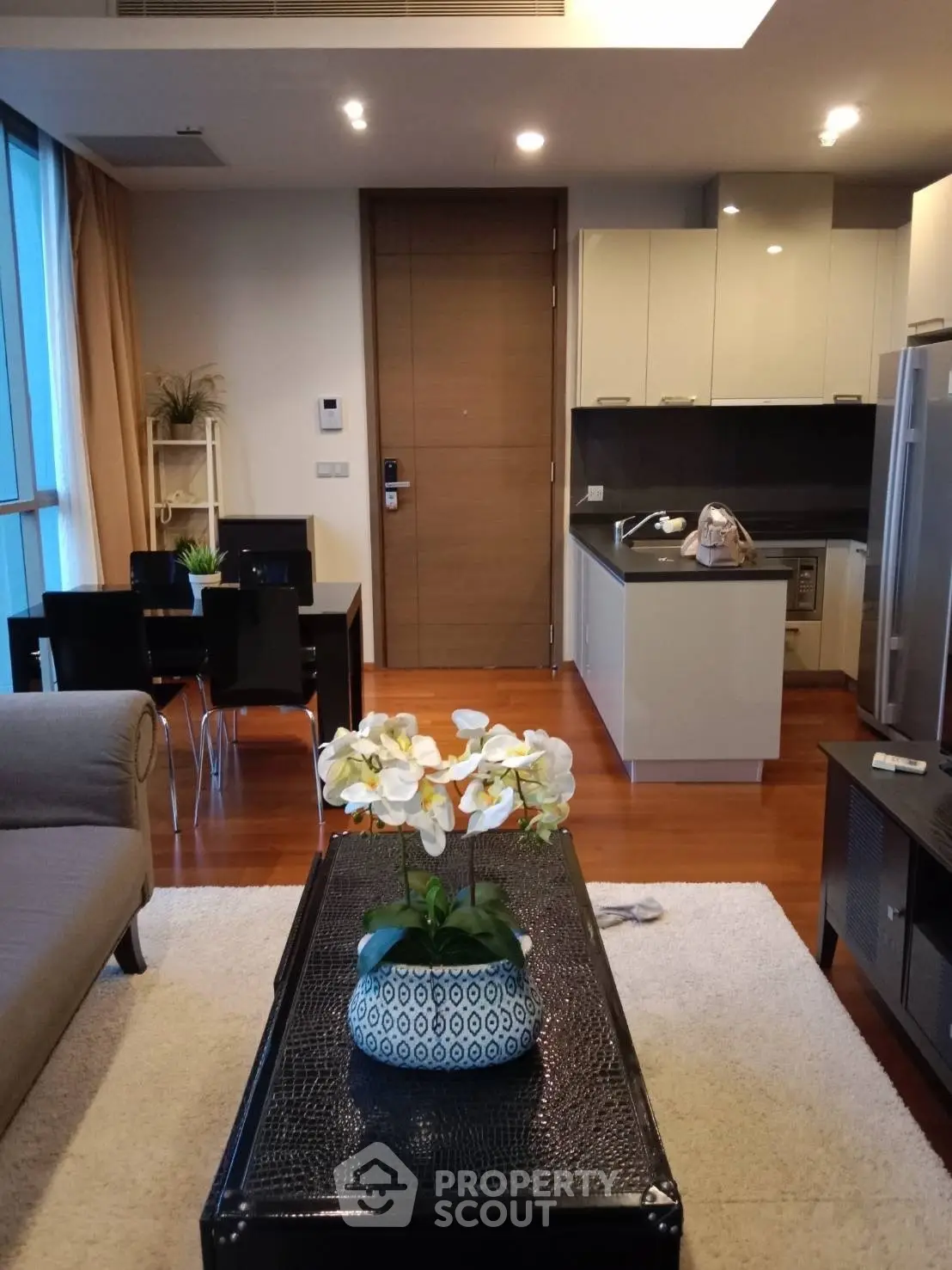 Modern open-layout living room with kitchen, featuring stylish decor and hardwood floors.