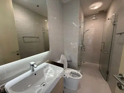 Modern bathroom with sleek fixtures and glass shower enclosure in a contemporary apartment.