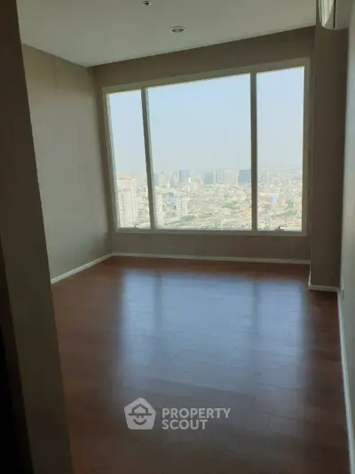 Spacious room with large window offering stunning city view, perfect for modern living.