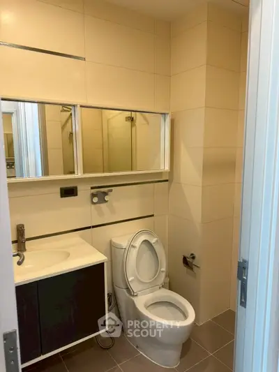 Modern bathroom with sleek fixtures and neutral tiles, featuring a compact design.