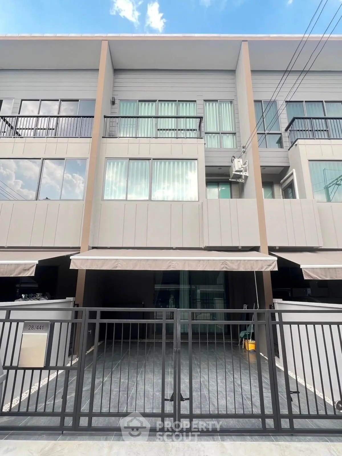 Modern townhouse exterior with gated entrance and large windows