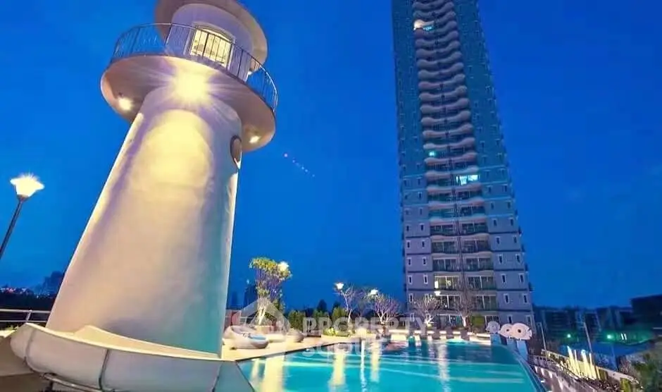 Luxurious high-rise building with illuminated pool and unique lighthouse feature at dusk.