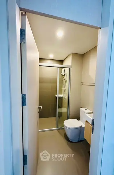 Modern bathroom with sleek shower and toilet in contemporary apartment.