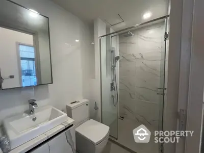 Sleek modern bathroom with marble tiling, glass shower enclosure, and stylish vanity for a luxurious living experience.