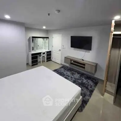 Modern bedroom with sleek furniture and wall-mounted TV in a stylish apartment.