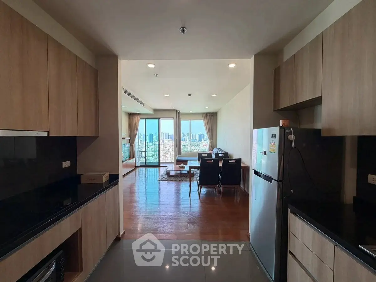Spacious open-plan kitchen and living area with stunning city views, modern appliances, and elegant wooden flooring.