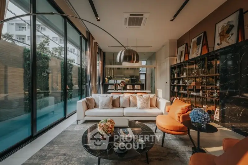 Luxurious modern living room with pool view, elegant decor, and ample natural light.