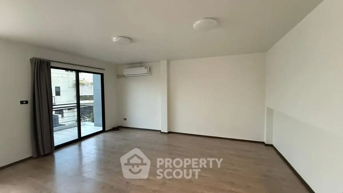 Spacious empty living room with balcony access and modern air conditioning unit.