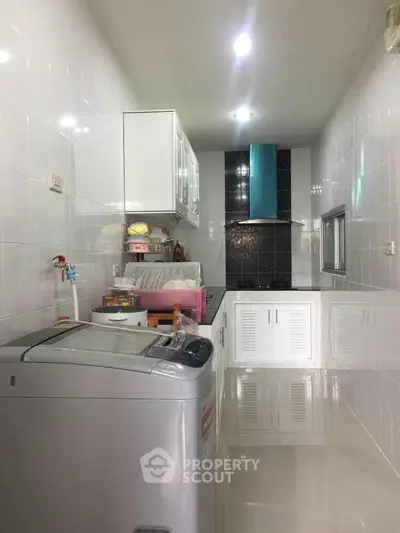 Modern kitchen with sleek white cabinets and washing machine in a compact layout.
