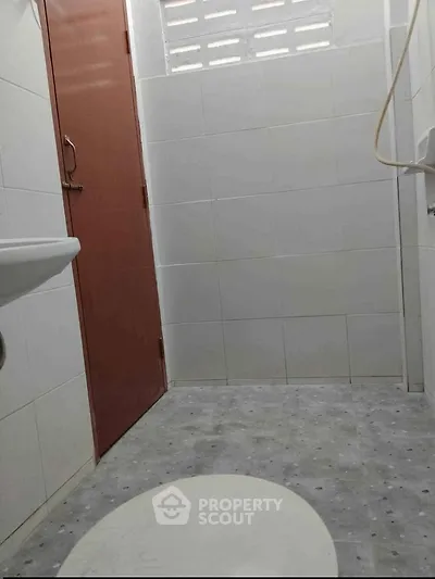 Compact bathroom with tiled walls and floor, featuring a simple design and minimal fixtures.
