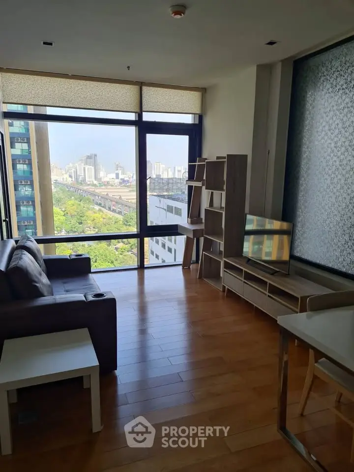 Modern living room with large window offering stunning city view, stylish furniture, and wooden flooring.