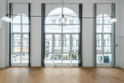 Spacious room with large arched windows and elegant wooden flooring