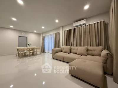 Spacious modern living room with elegant beige sofa and dining area, perfect for family gatherings.