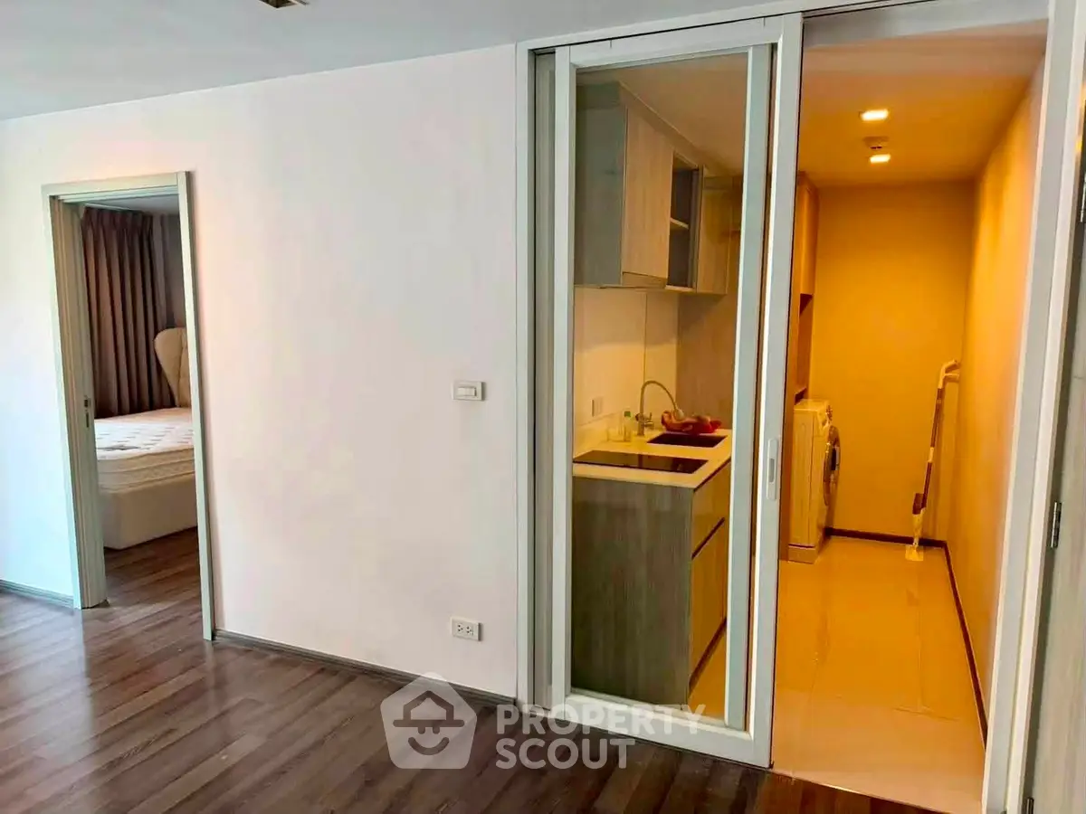 Modern apartment interior with sleek kitchen and cozy bedroom, featuring wooden flooring and contemporary design.