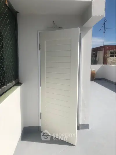Rooftop access door on a sunny day with clear sky and urban surroundings.