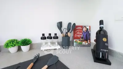 Modern kitchen countertop with utensils, wine bottle, and decor plants.