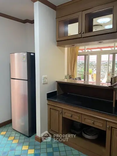 Charming kitchen with wooden cabinetry and modern fridge, featuring colorful tiled flooring and open layout.