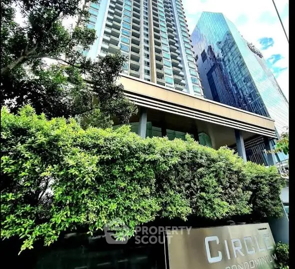 Modern high-rise condominium with lush greenery and sleek architecture.