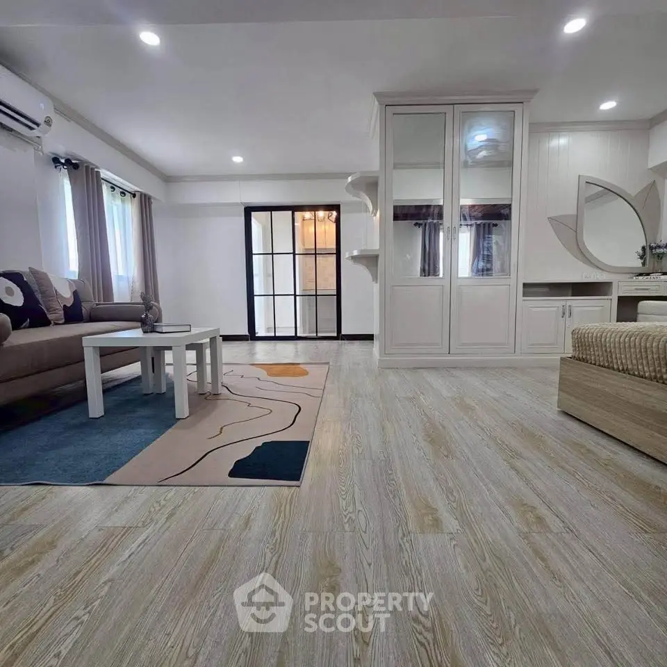 Spacious living room with modern decor and elegant flooring, featuring a cozy seating area and stylish furnishings.
