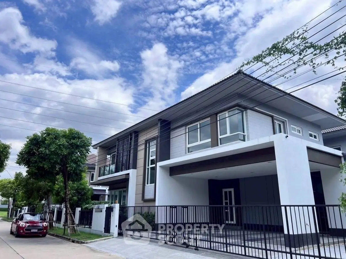 Modern two-story house with sleek design and spacious driveway under a clear blue sky.