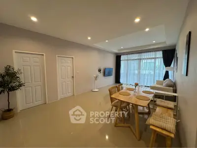 Spacious living room with modern decor and dining area, featuring large windows and stylish furniture.