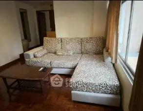 Spacious living room with stylish patterned sofa and wooden coffee table, perfect for relaxation.