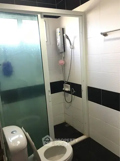 Modern bathroom with shower and toilet in sleek black and white design.