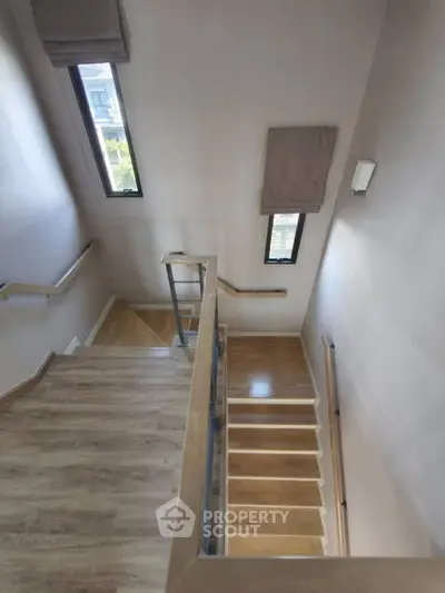 Modern staircase with wooden steps and sleek railing in a bright home interior
