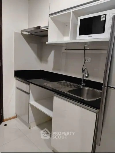 Modern kitchen with sleek black countertops and built-in microwave, perfect for urban living.