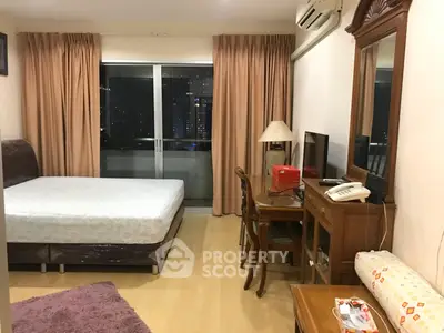 Cozy bedroom with city view, featuring a bed, desk, and balcony access in a modern apartment.